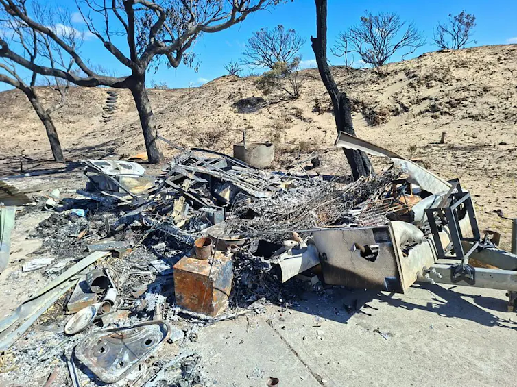 The burnt wreck of a shack and caravan after bushfires in Tasmania.