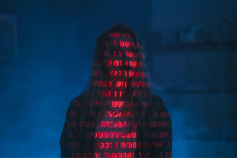 Red code projected over the silhouette of a woman on a dark blue background.