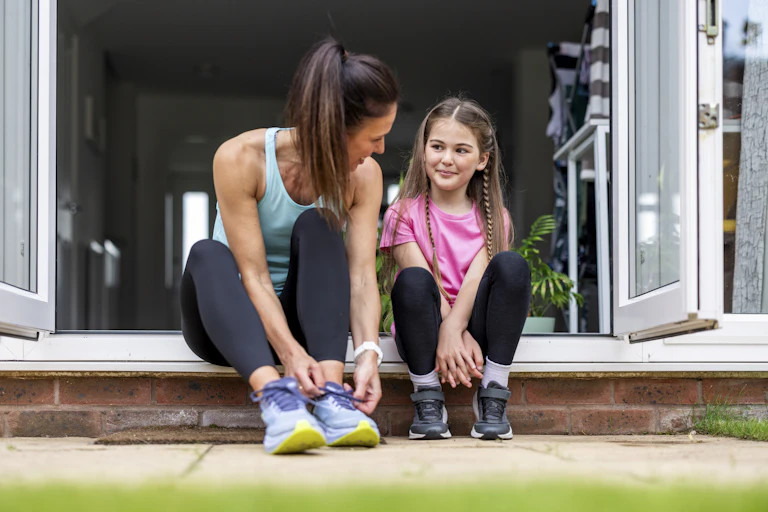 A mother sits next to her child putting on their shoes