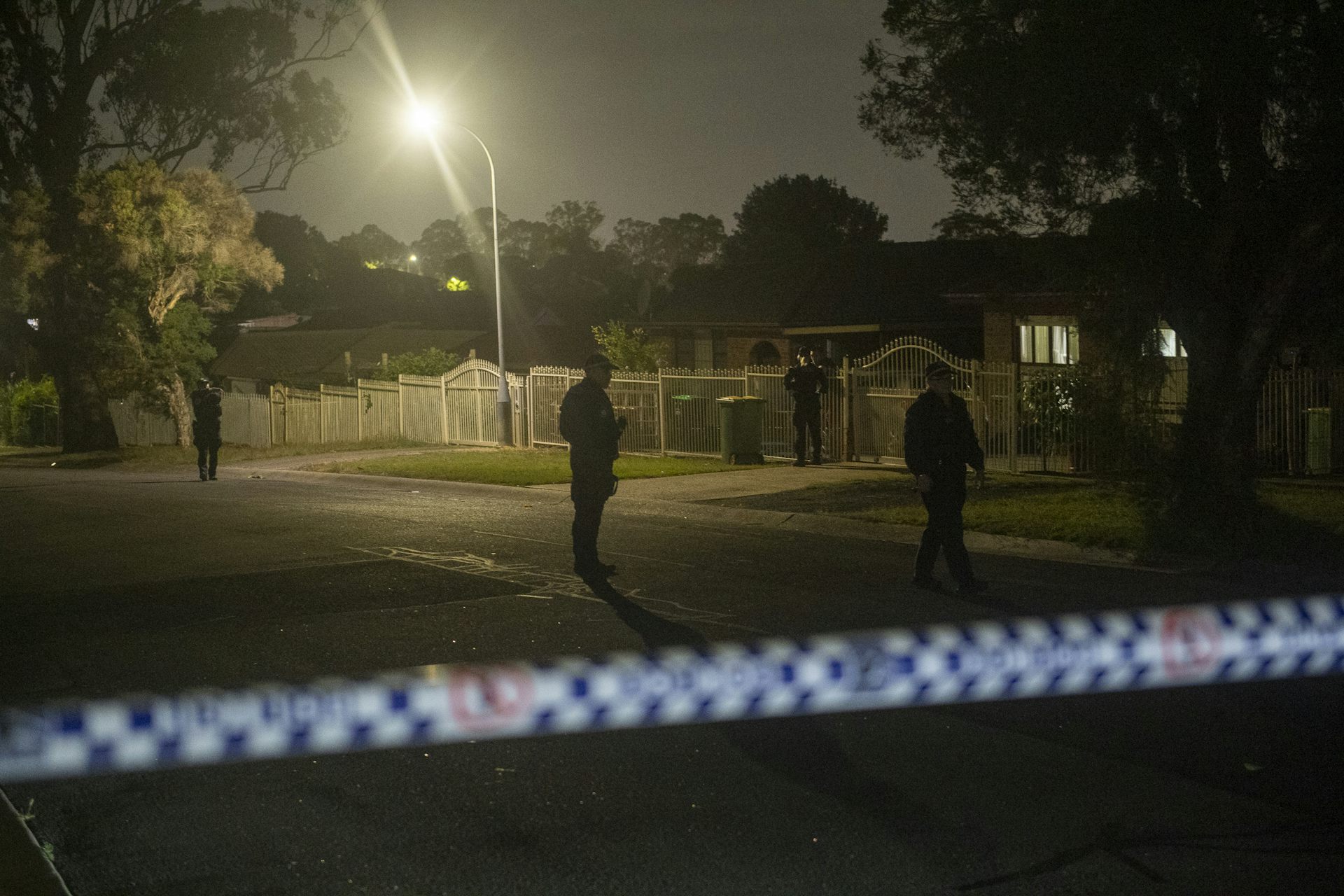 A suburban street at nighttime behind police tape