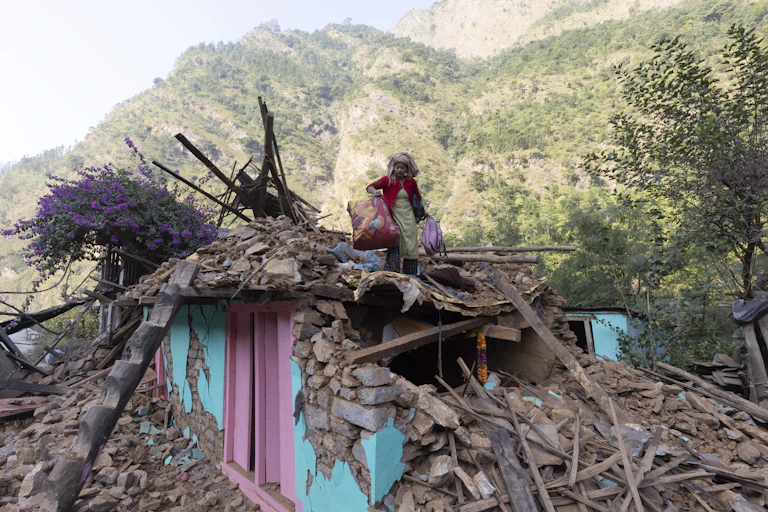 A woman holds her bags amidst the rubble of an earthquake in Nepal.