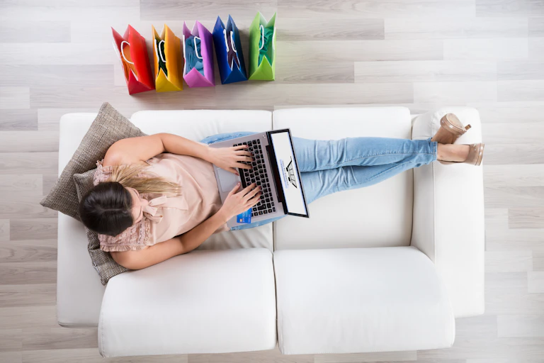 Woman on sofa using laptop to shop.