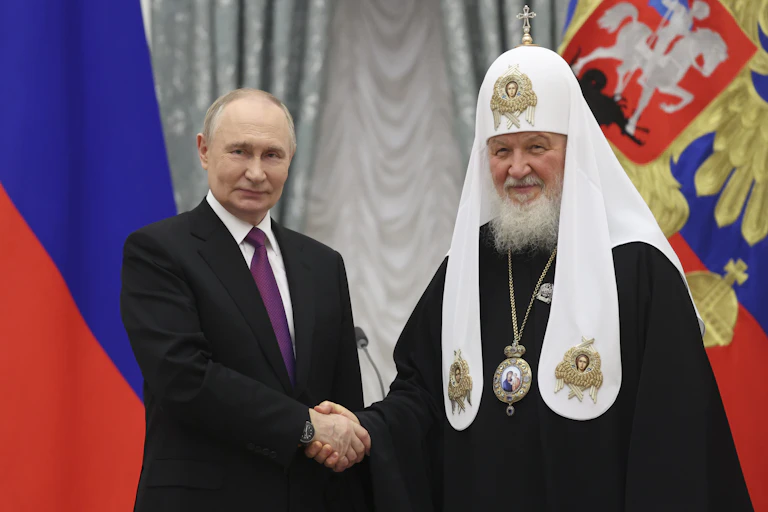 Patriarch Kirill and Vladimir Putin shaking hands.