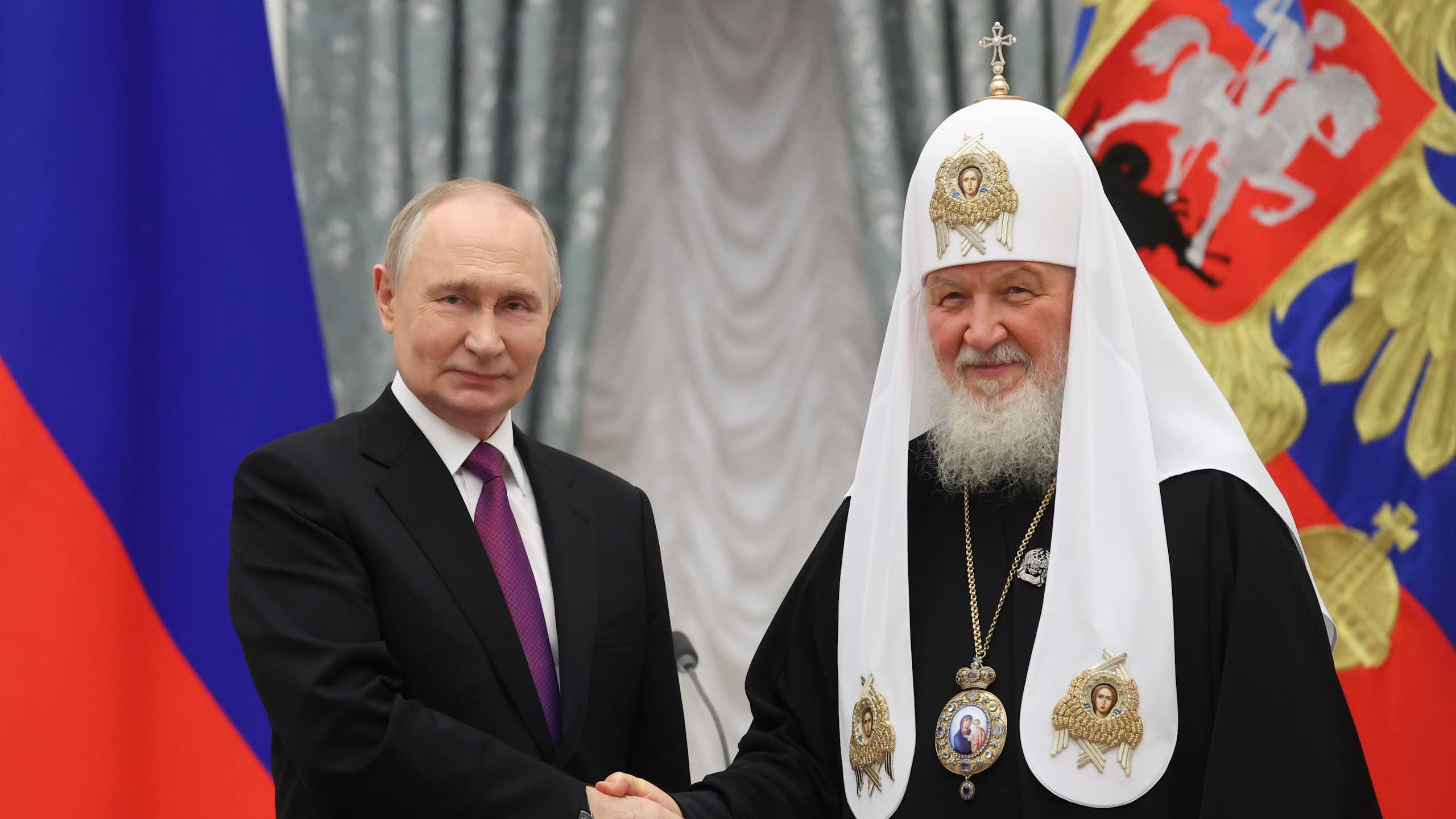 Patriarch Kirill and Vladimir Putin shaking hands.