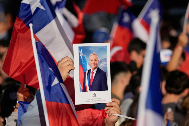 People hold flags and a picture of their leader at a political rally.