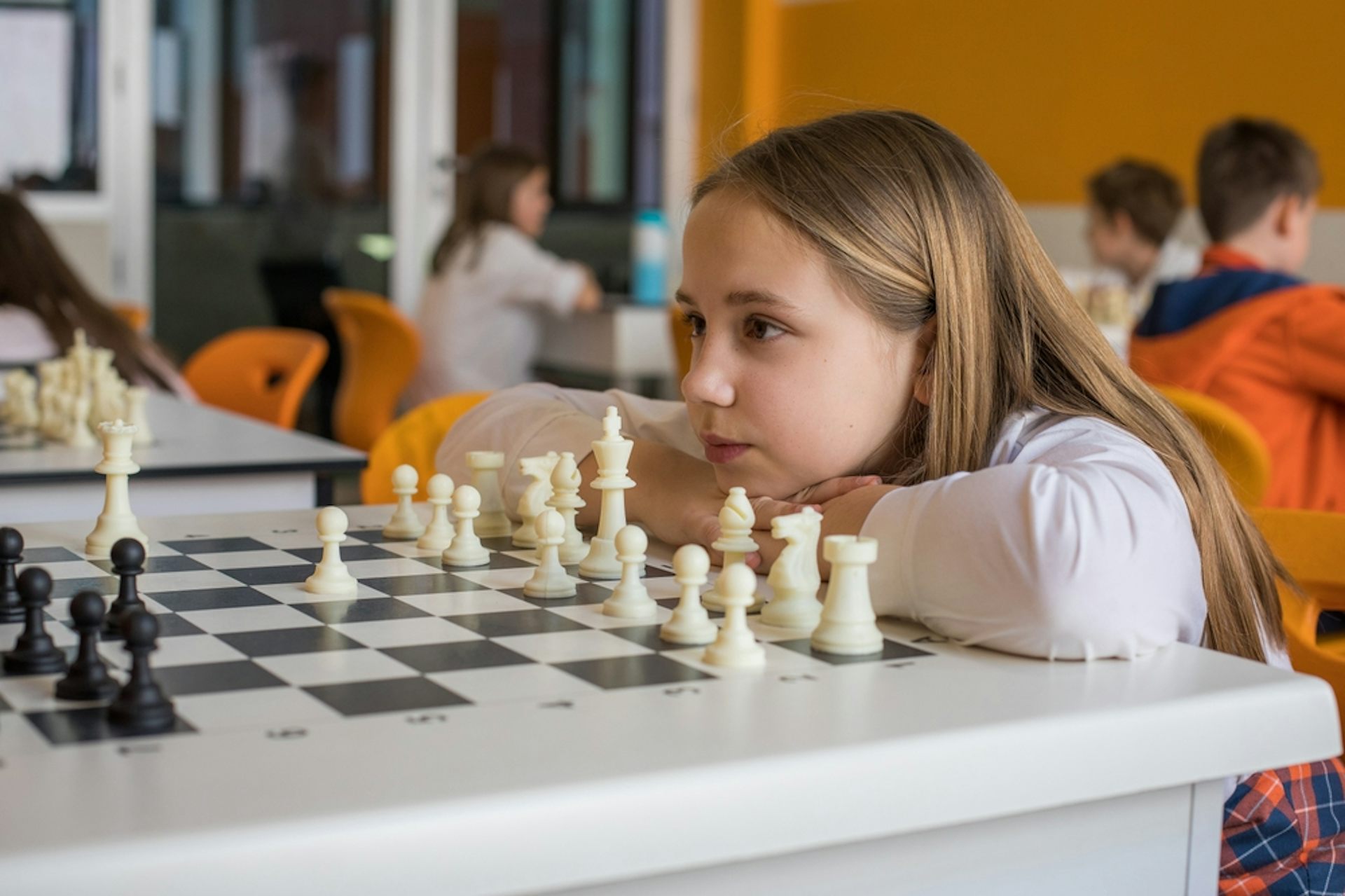 Une petite fille en classe face à un jeu d'échecs