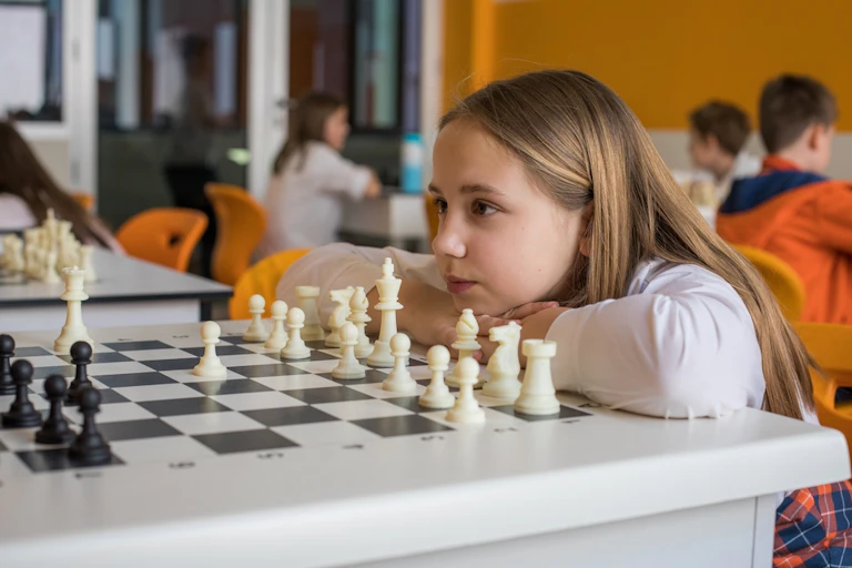 Une petite fille en classe face à un jeu d'échecs