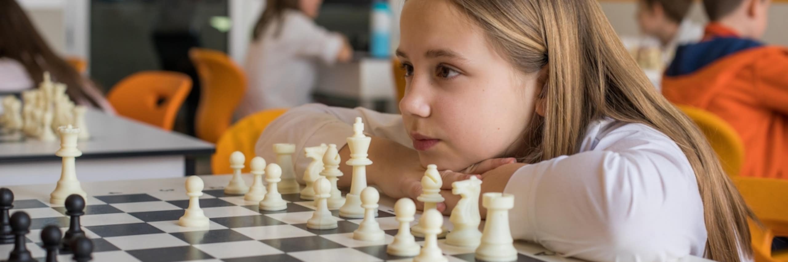 Une petite fille en classe face à un jeu d'échecs
