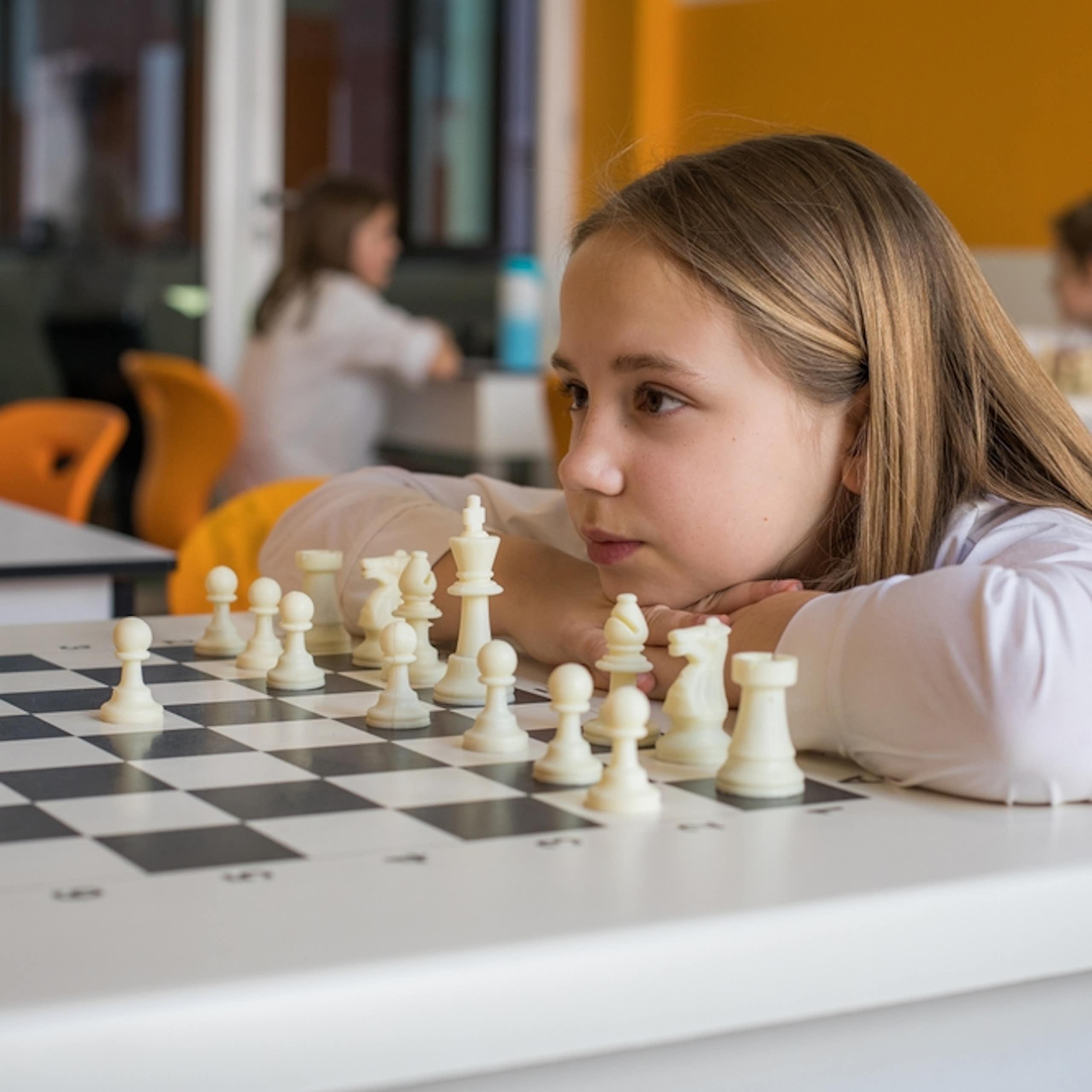 Une petite fille en classe face à un jeu d'échecs
