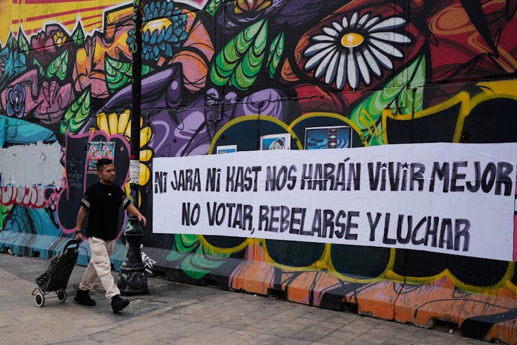 Una persona pasa junto a un mural político pintado con spray.