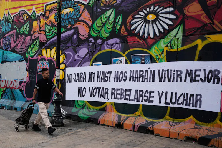 A person walks by a spray-painted political mural.
