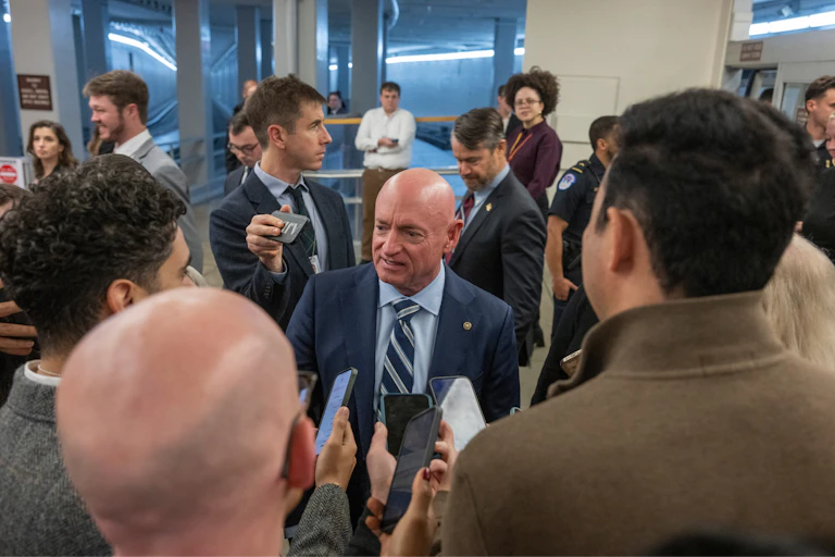A man speaks to several reporters.