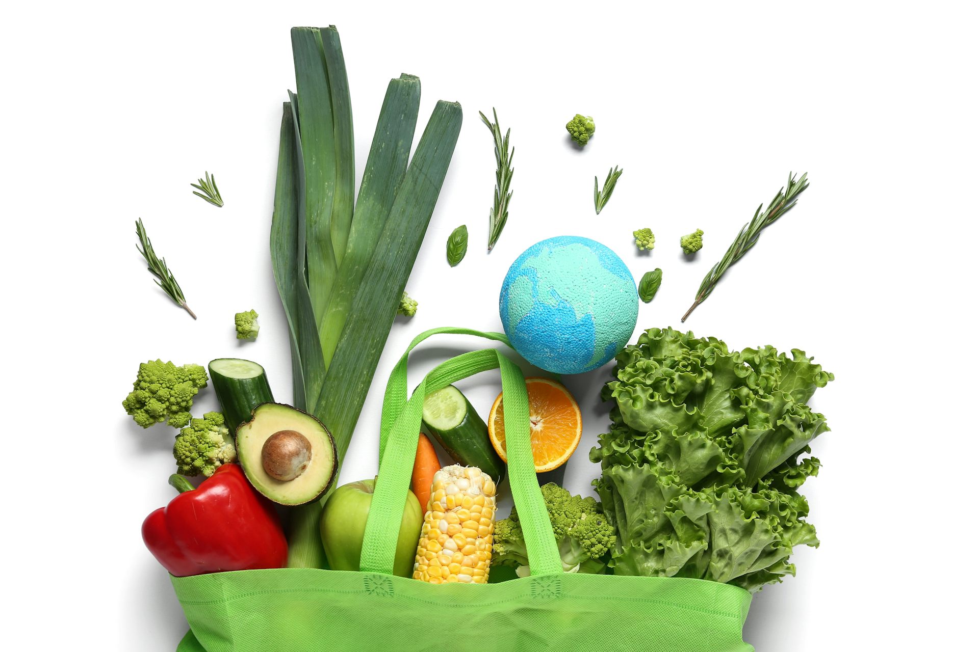 Verduras y una bola del mundo de poliestireno saliendo de una bolsa de tela de la compra verde