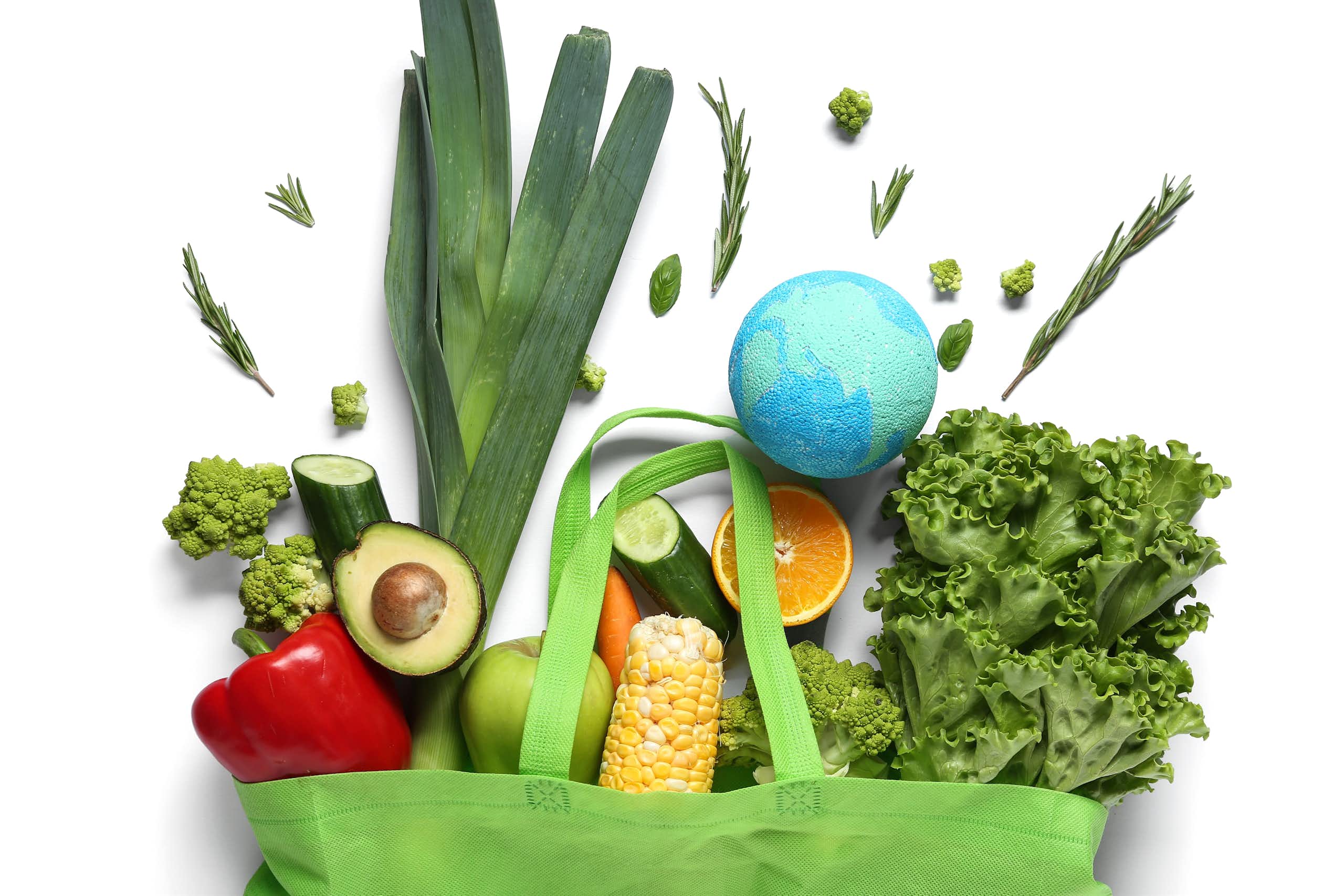 Verduras y una bola del mundo de poliestireno saliendo de una bolsa de tela de la compra verde