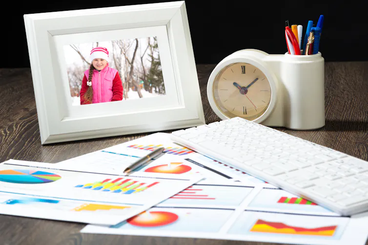 work papers scattered on a desk with a framed photo of a young child in the background.