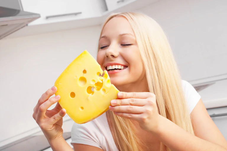 Smiling woman about to eat huge chunk of cheese