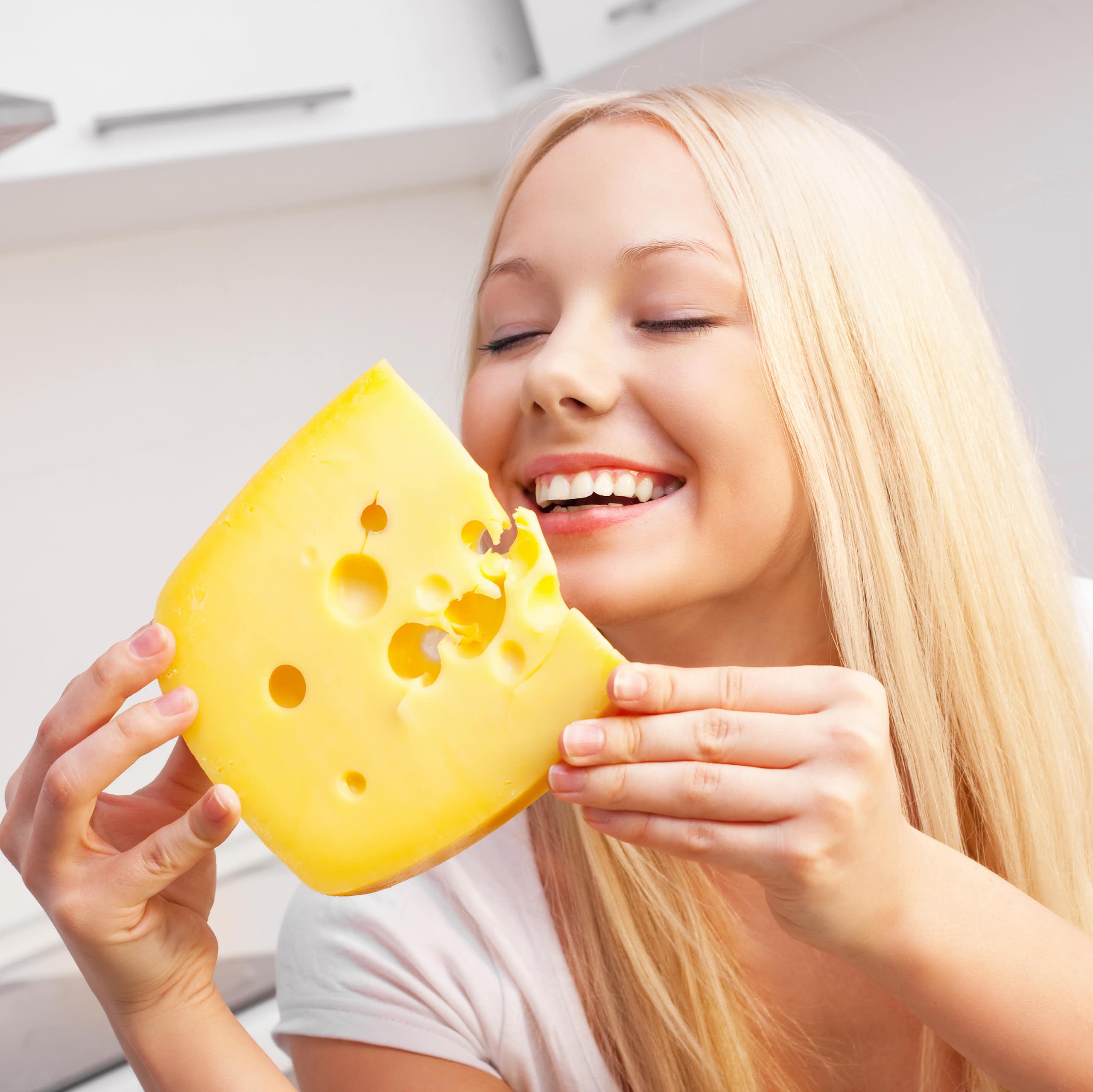 Smiling woman about to eat huge chunk of cheese