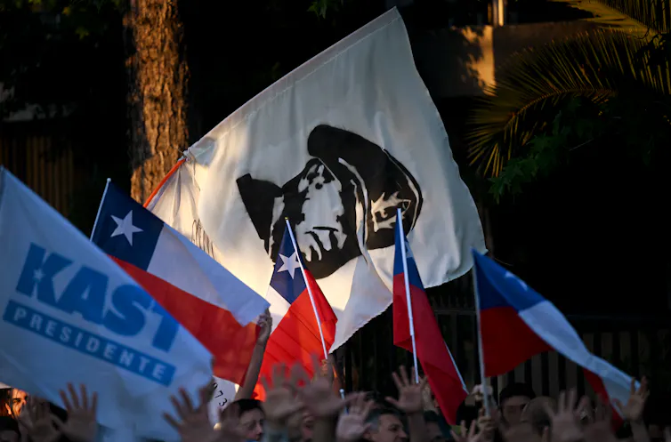 Supporters at a political rally wave flags.