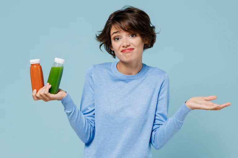 Woman shrugs while holding two detox juices