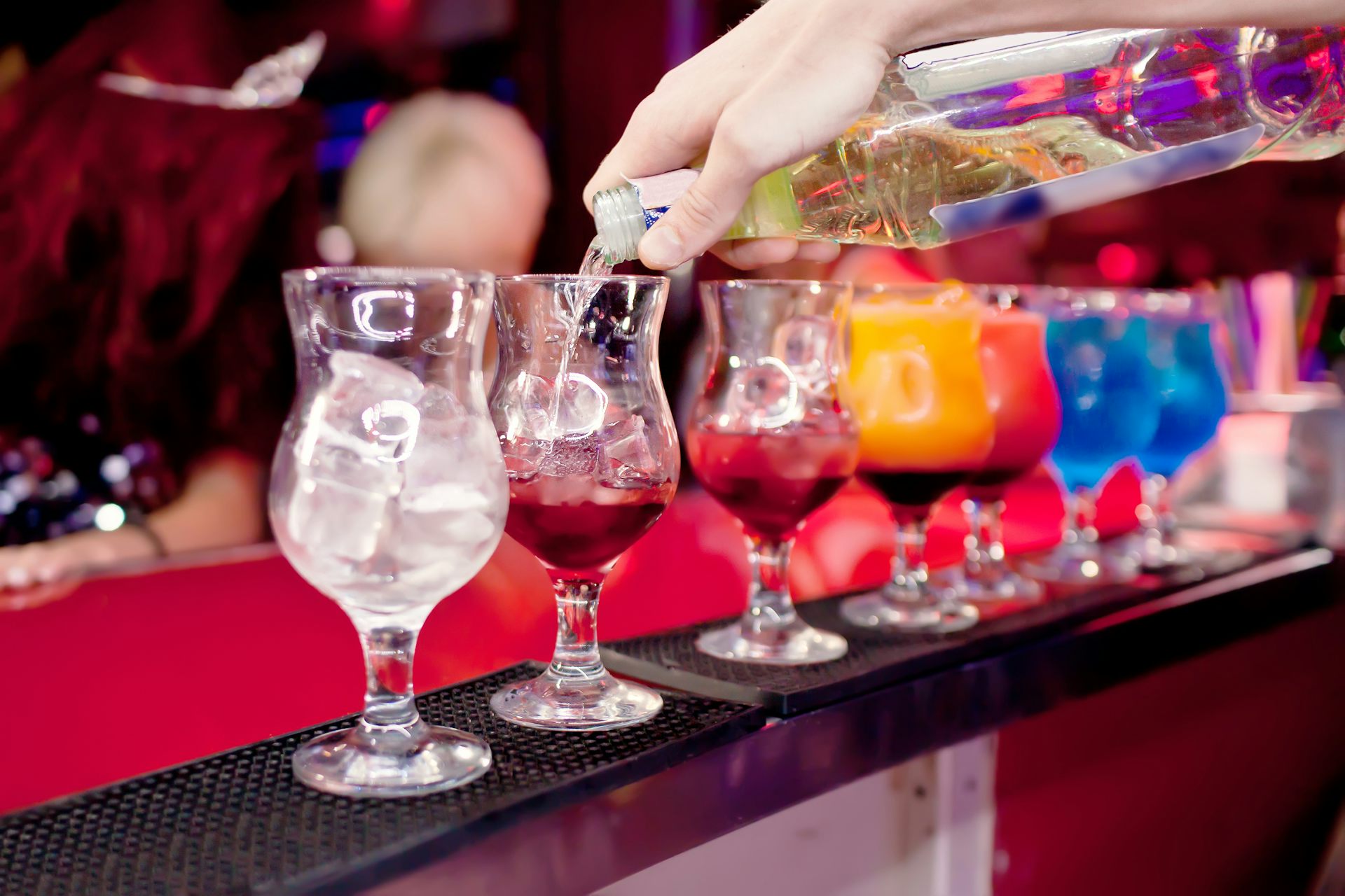 Close up of colourful cocktails being prepared at a bar