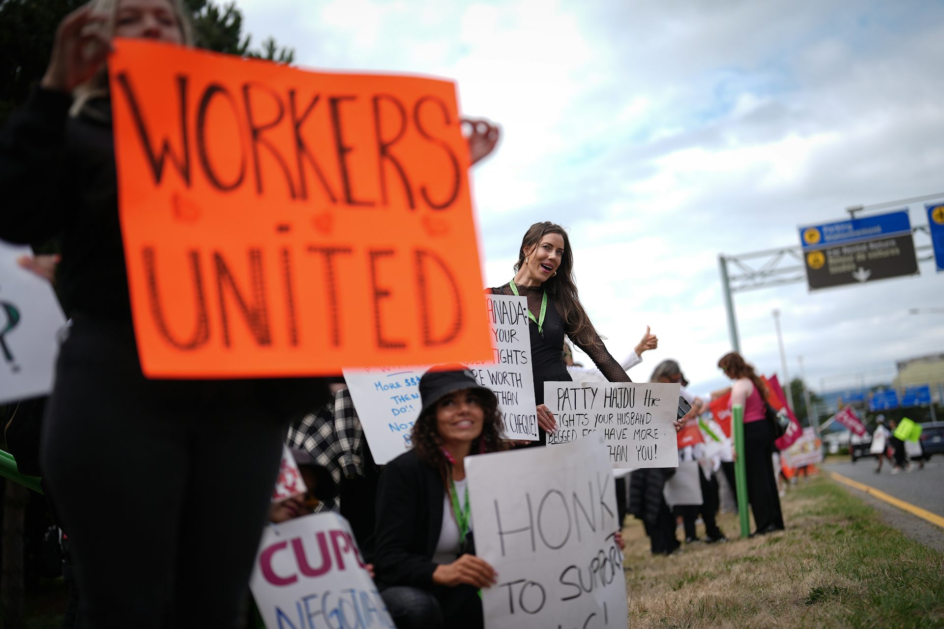 Striking workers hope up signs. An orange sign in the foreground reads Workers United.