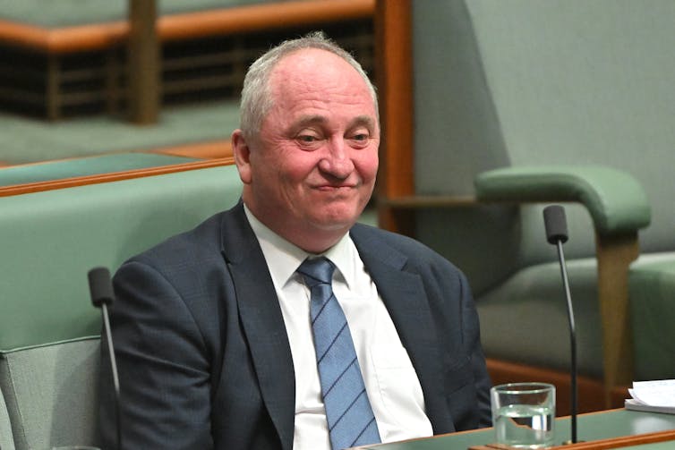 A red-faced man in a suit sits in the House of Representatives