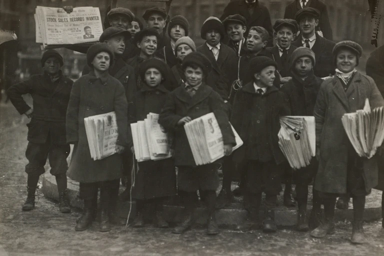 A historical photo of a group of young newspaper delivery boys in winter coats