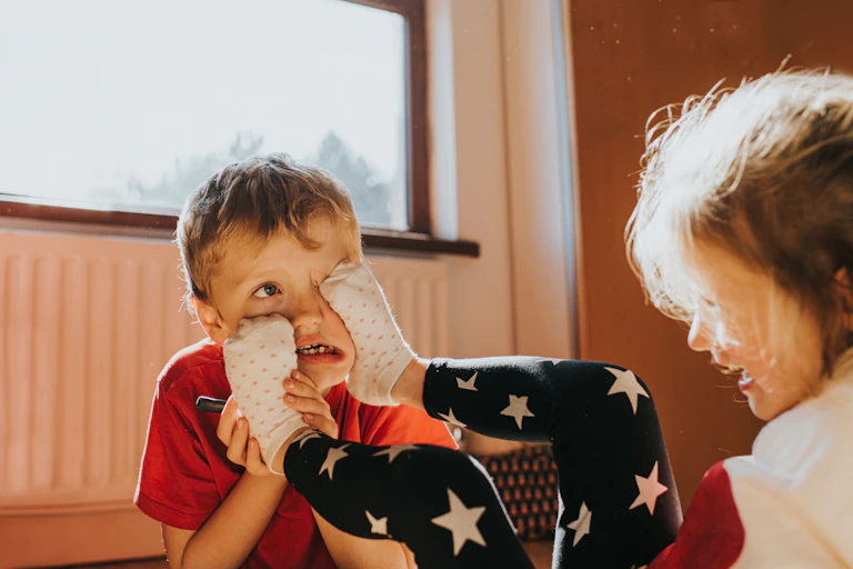 A small child sticks her feet in another child's face