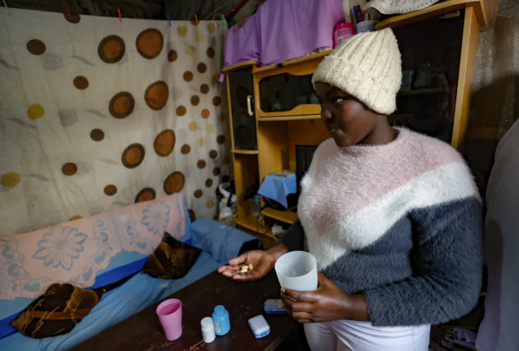 Person standing in room, holding pills in hand