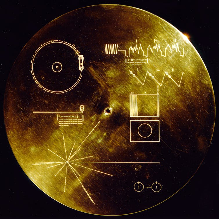 Circular gold-plated cover displaying symbols and diagrams.
