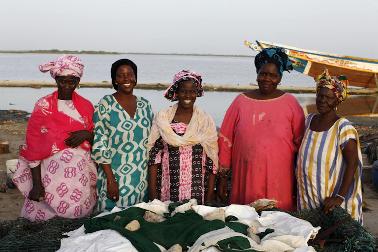 Femmes d'une coopérative devant un bateau en Afrique.