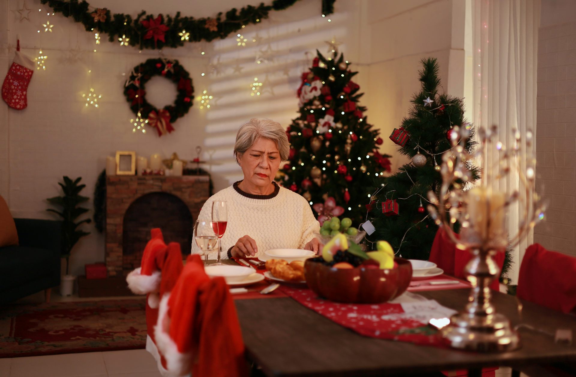 Una señora cena sola en una casa con adornos navideños