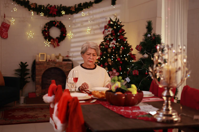 Una señora cena sola en una casa con adornos navideños