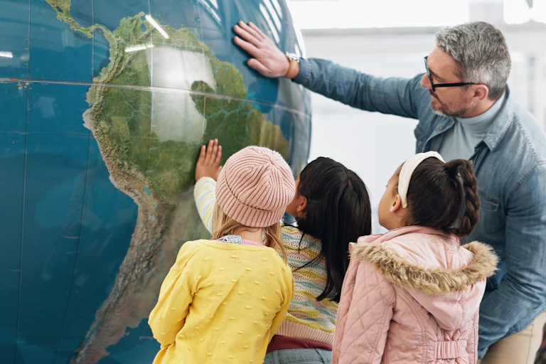 Teacher and children look at giant globe
