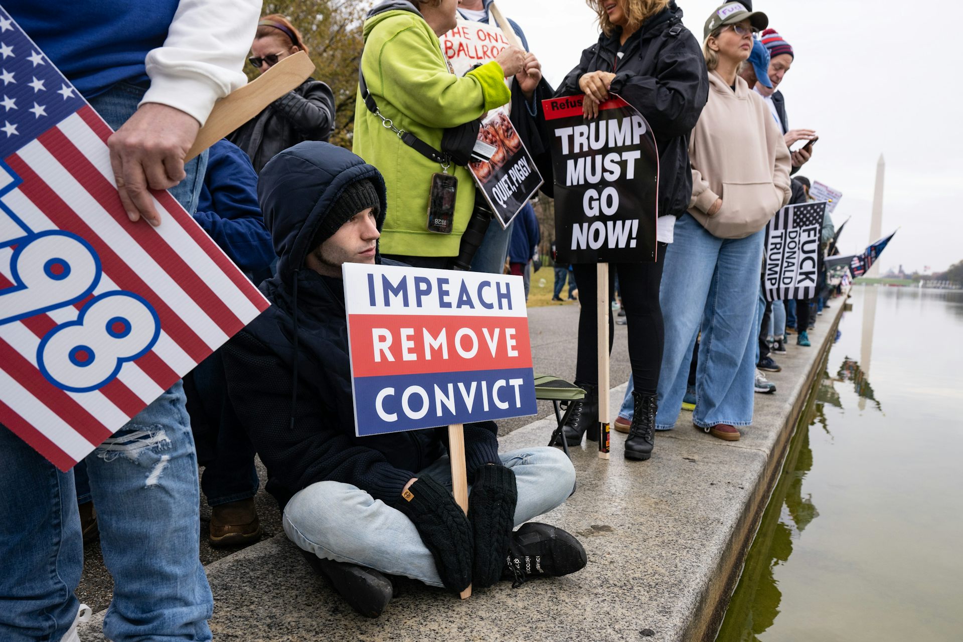 A protester holding a sign that reads 'impeach, remove, convict'.