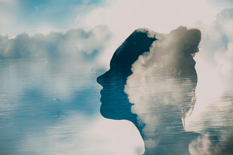 Abstract image of outline of woman's head over image of the ocean
