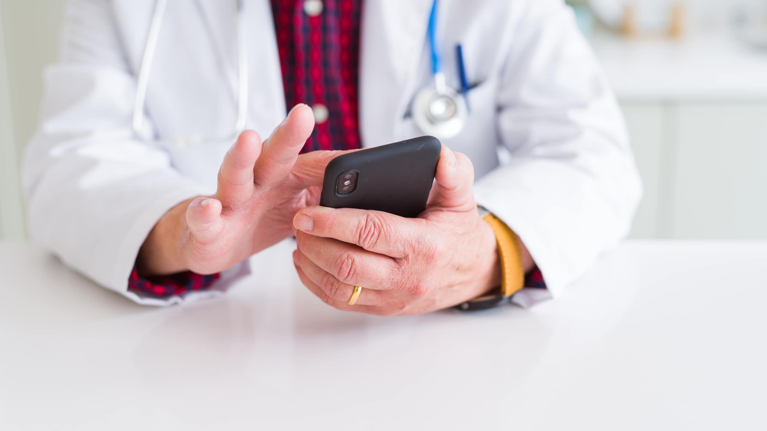 Doctor tapping on his mobile phone.