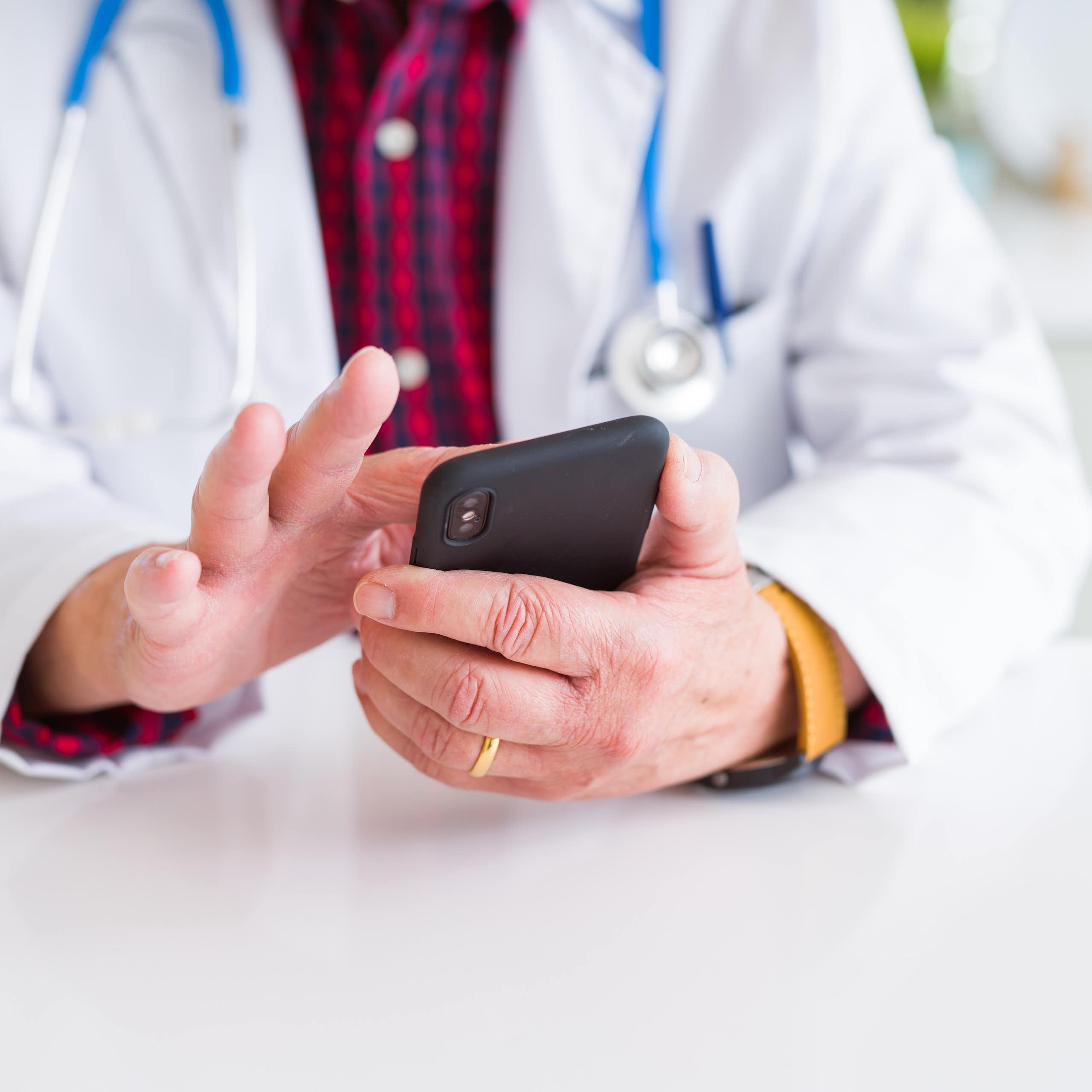 Doctor tapping on his mobile phone.