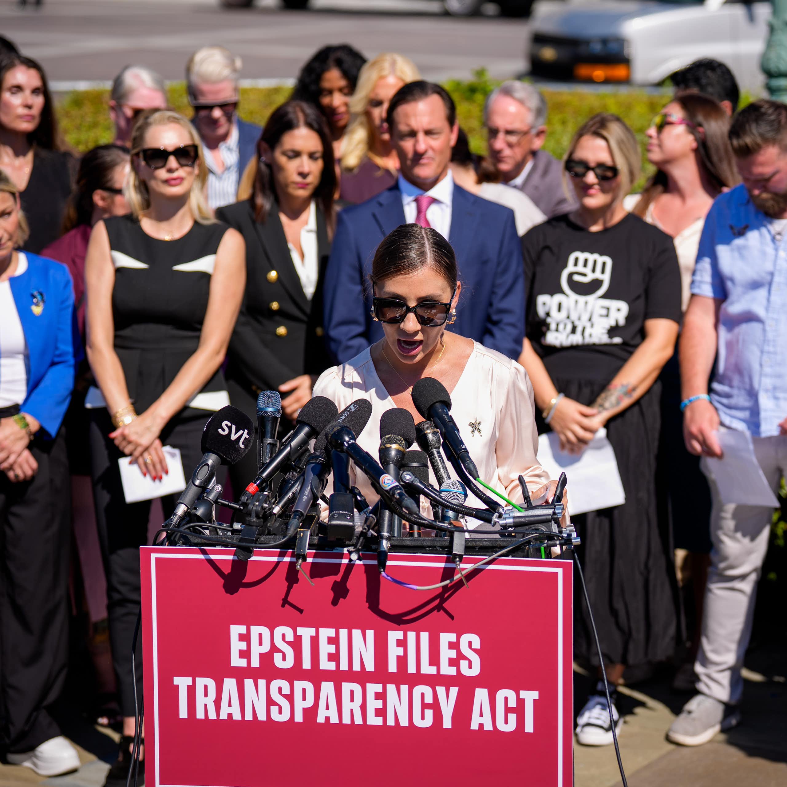 A woman speaks at a lectern with a sign on it that says "Epstein Files Transparency Act"