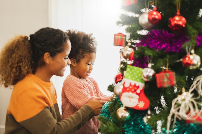 A woman and a child decorating a Christmas tree