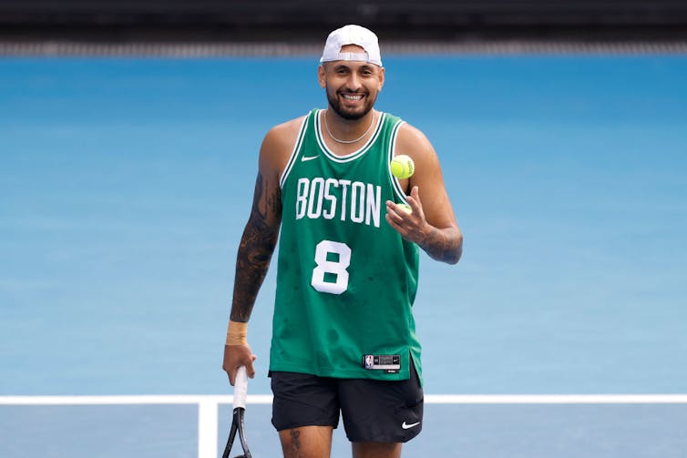 Tennis is about for a ‘Battle of the Sexes’ sequel – with out a motion in the back of it 2 Young man smiling while holding a tennis racket and a tennis ball, wearing a green basketball jersey and a backward white cap.
