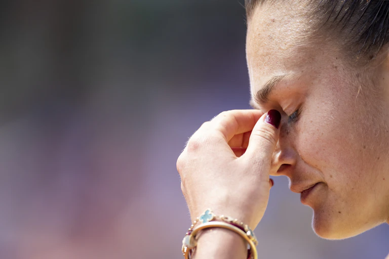 Side profile of your woman with her eyes closed and her hand rubbing her eyes.