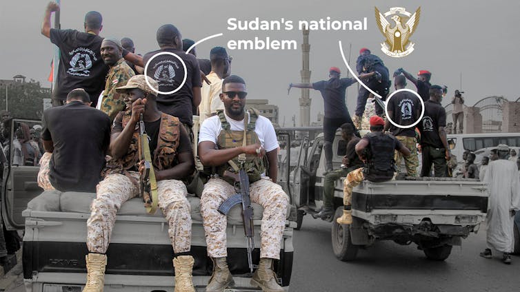 Men holding guns and in army gear sit on trucks