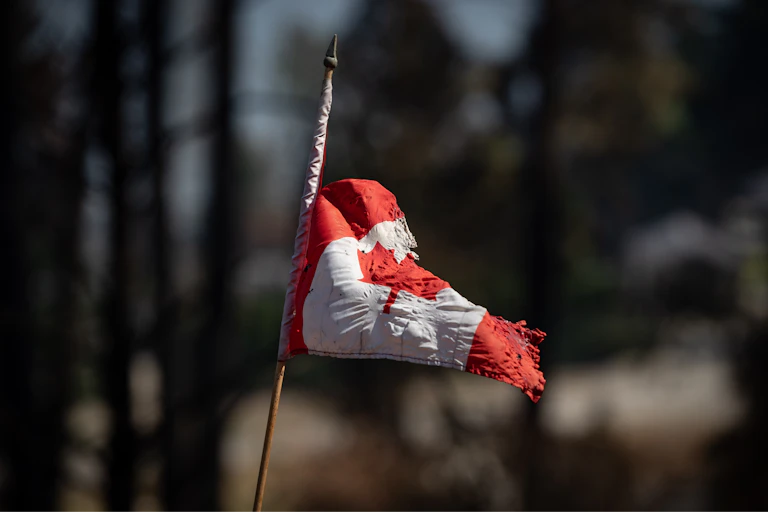 A tattered canadian flag on a pole