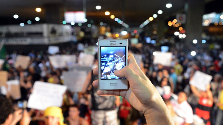Close up of a smartphone being used to take a photograph of a protest.