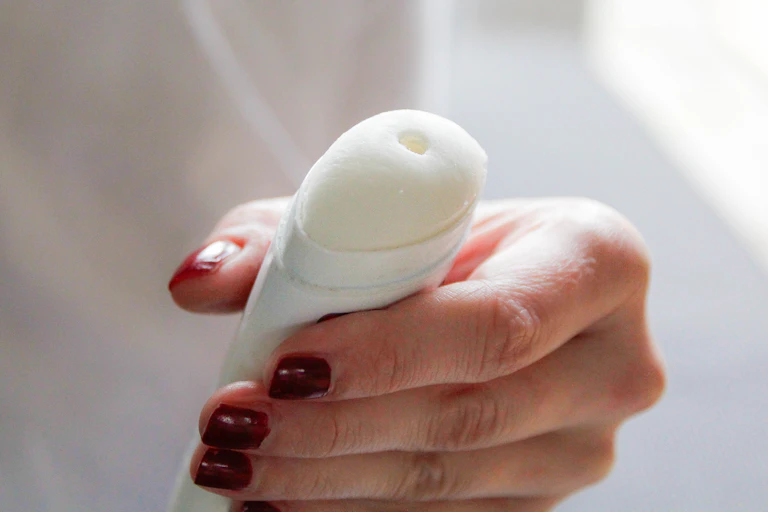 Close-up of a hand holding a white deodorant stick.