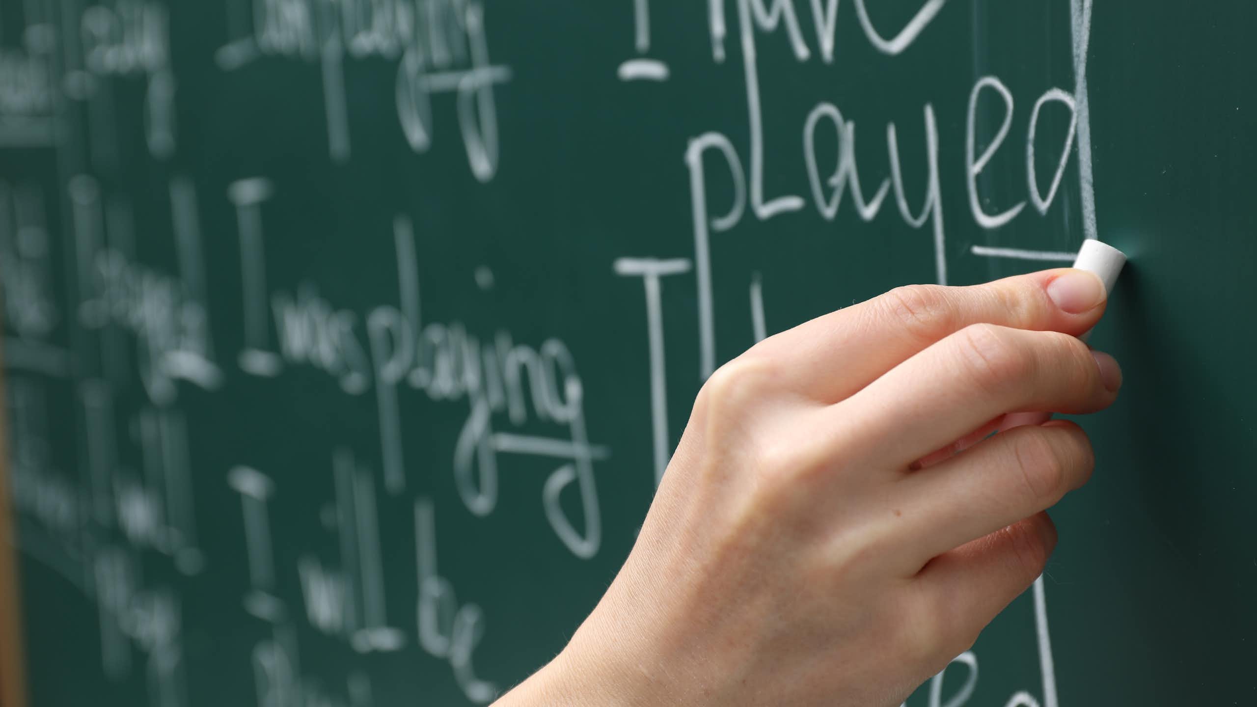 A hand writing english words on a chalkboard