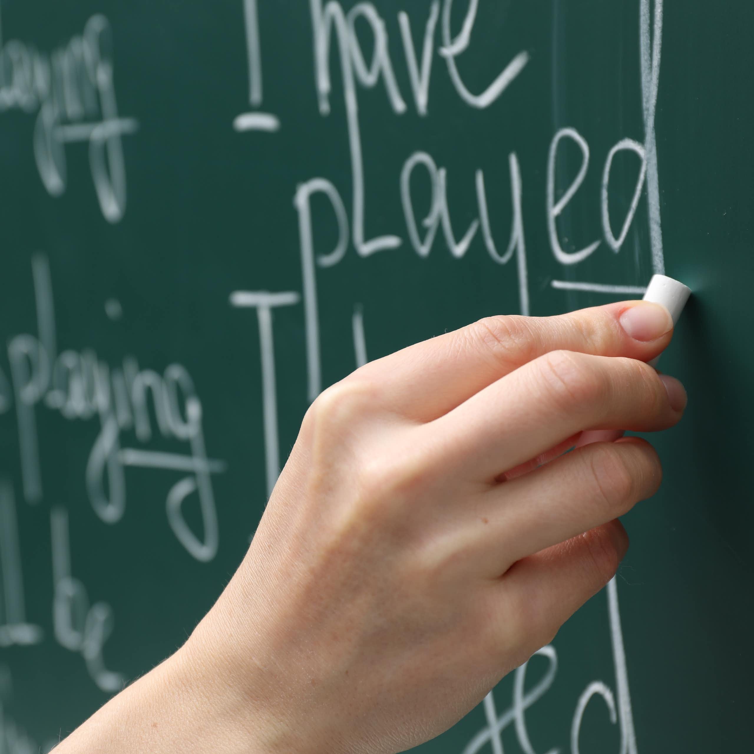 A hand writing english words on a chalkboard
