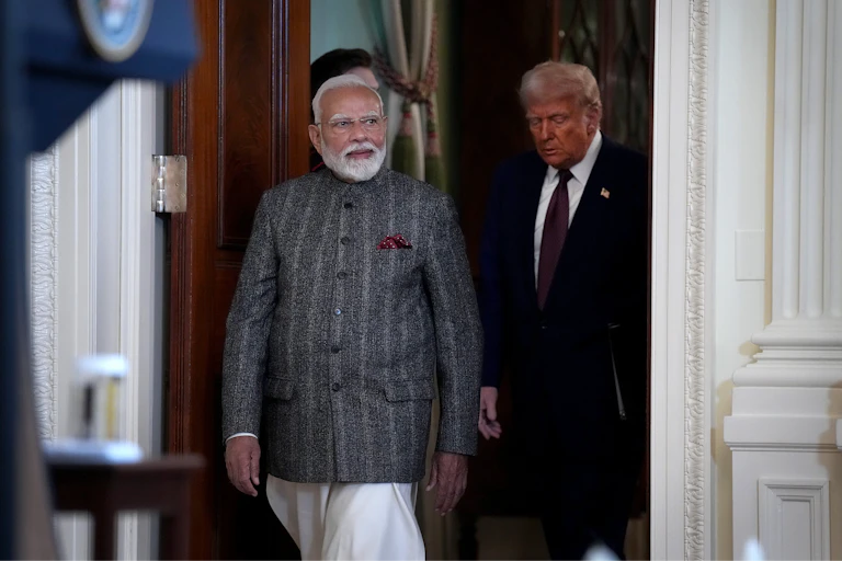 Two men walk through a door.