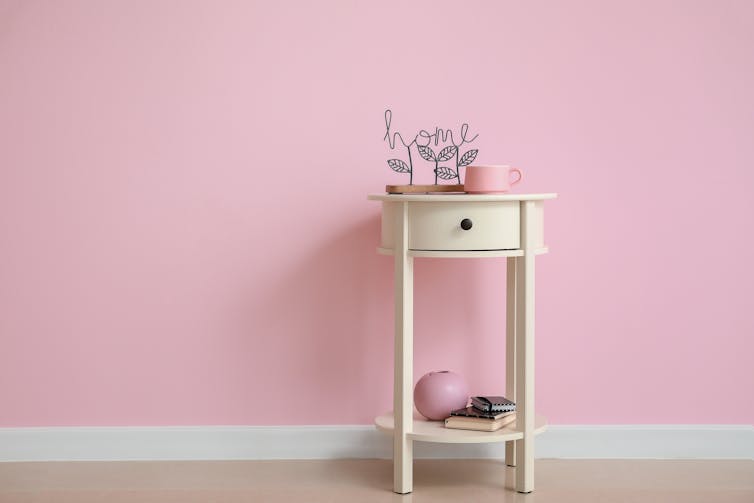 A pink wall with white side table.
